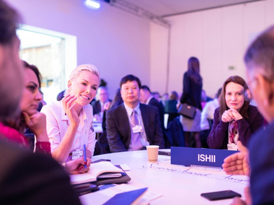 Hier sieht man eine Gruppe von Event-Managern, die an einem Tisch sitzt und die Grundlagen des Event-Managements besprechen.